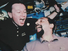 Maurizio Cheli e Umberto Guidoni alle prese con un pezzo di Parmigiano Reggiano durante STS-75. (c) NASA