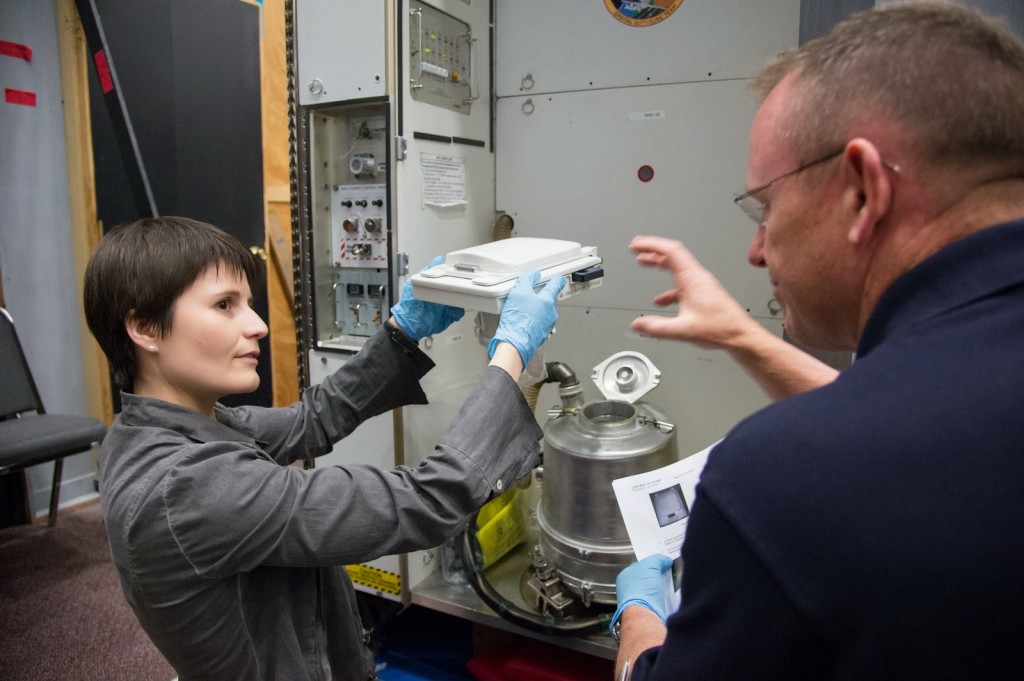 Samantha Cristoforetti sostituisce il contenitore dei rifiuti solidi della toilette nel mockup della ISS al JSC. Fonte: NASA/Harnett