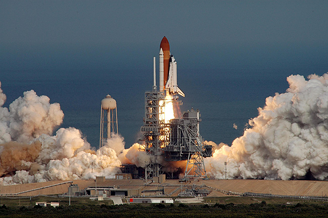 Sullo sfondo del blu dell'Oceano Atlantico, lo Space Shuttle decolla dal Kennedy Space Center con il suo equipaggio di 7 astronauti - L'inizio della missione STS-122 verso la ISS. Credit: NASA/Jim Grossmann.