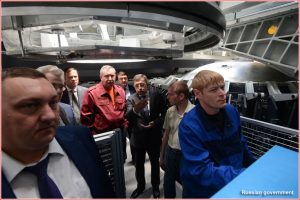 Head of GKNPTs Khrunichev Andrei Kalinovsky explains the work of machinists welding components of the Angara rocket at PO Polyot to Deputy Prime Minister Dmitry Rogozin (in red jacket) and head of Roskosmos Igor Komarov (to Rogozin's left).